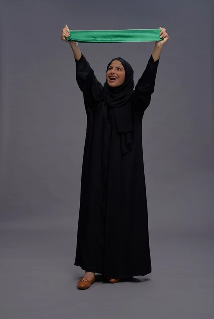 امرأة سعودية ترفع علم المملكة العربية السعودية في استوديو