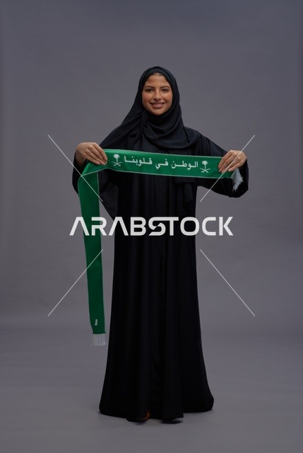 امرأة سعودية تمسك وشاح اليوم الوطني السعودي