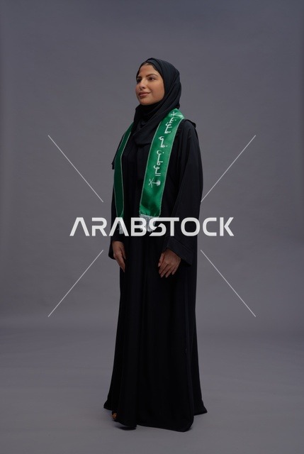 امرأة سعودية بالعباءة ووشاح اليوم الوطني الأخضر