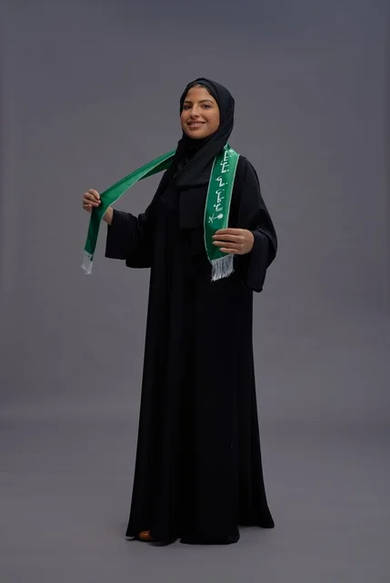 امرأة سعودية تحمل علم المملكة في استوديو