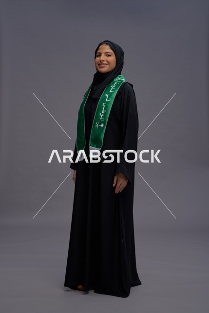 امرأة سعودية بالعباية والوشاح الوطني في استديو تصوير