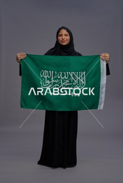 امرأة سعودية تحمل علم المملكة العربية السعودية بالاستوديو