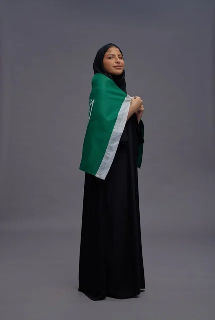 امرأة سعودية تحمل علم المملكة في الاستوديو