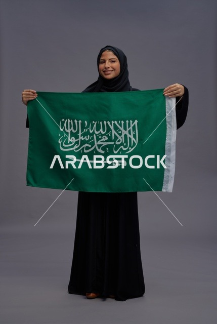 امرأة سعودية تمسك علم المملكة في الاستوديو