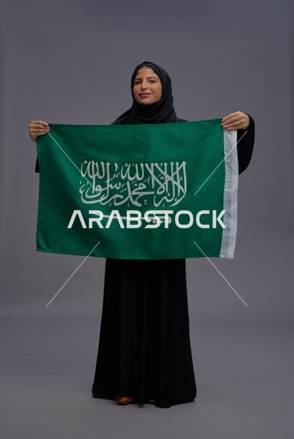 امرأة سعودية تحمل علم المملكة في الاستوديو