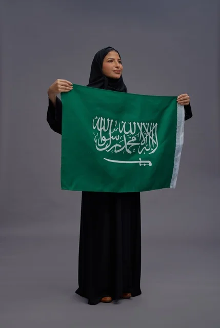 امرأة سعودية تحمل علم المملكة العربية السعودية