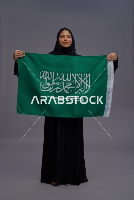 امرأة سعودية تحمل علم المملكة العربية السعودية في استوديو