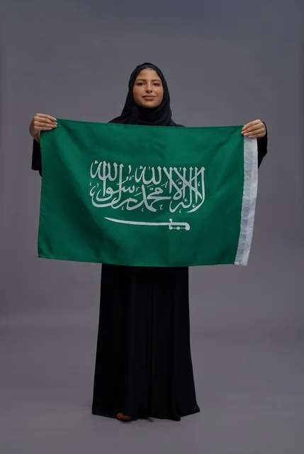 امرأة سعودية تحمل علم المملكة العربية السعودية في استوديو