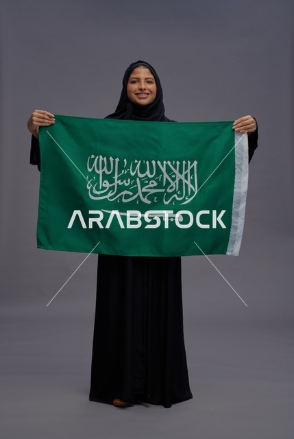 امرأة سعودية تحمل علم المملكة في الاستوديو