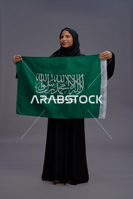 امرأة سعودية تحمل علم المملكة العربية السعودية في استوديو