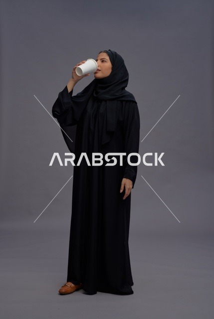 امرأة سعودية بعباءة سوداء تشرب القهوة في الاستوديو