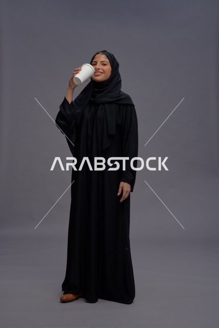 امرأة سعودية بالعباءة السوداء تحمل كوب قهوة