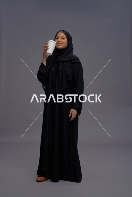 امرأة سعودية بعباءة سوداء تحمل كوب قهوة