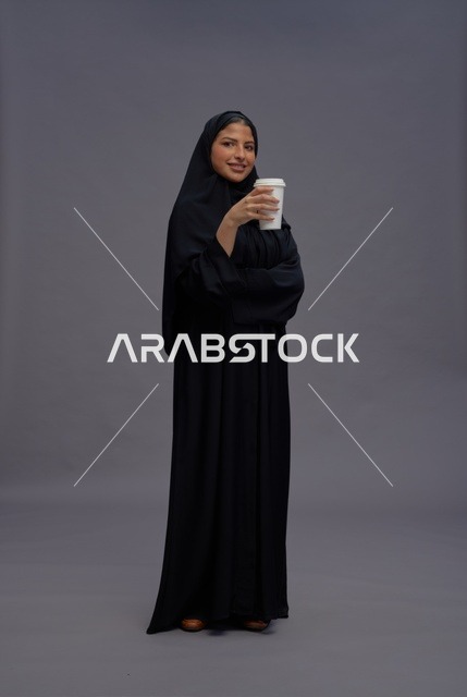 امرأة سعودية بعباءة سوداء تحمل كوب قهوة