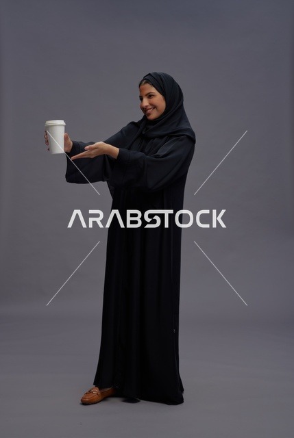 امرأة سعودية بعباءة سوداء تحمل كوب قهوة