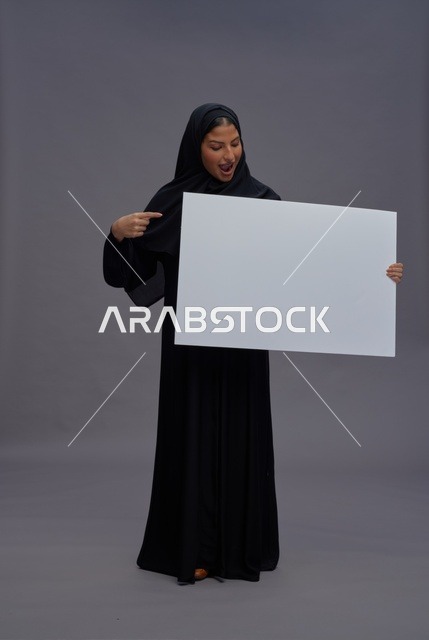 امرأة سعودية بعباية سوداء تحمل لوحة بيضاء فارغة