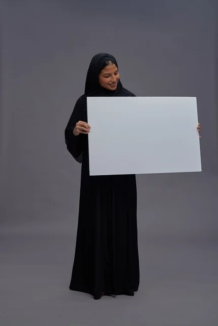 امرأة سعودية بعباية سوداء تحمل لوحة بيضاء فارغة امرأة سعودية بعباية سوداء تحمل لوحة بيضاء فارغة