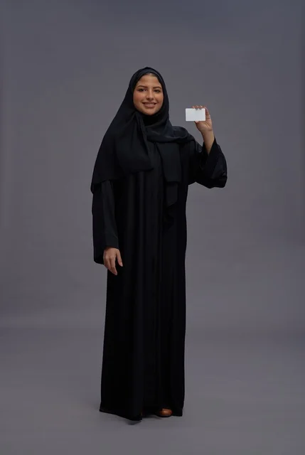 امرأة سعودية بالعباءة السوداء تحمل بطاقة بيضاء فارغة