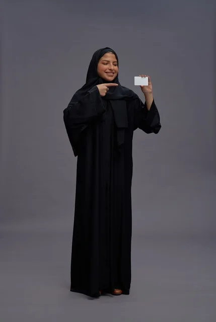 امرأة سعودية بعباية سوداء تحمل بطاقة بيضاء فارغة