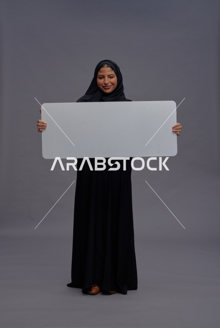 امرأة سعودية بعباءة سوداء تحمل لوحة بيضاء فارغة