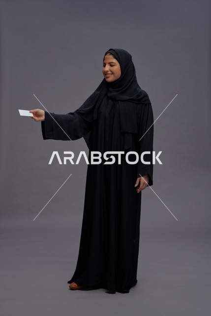 امرأة سعودية بالعباية تحمل بطاقة عمل فارغة