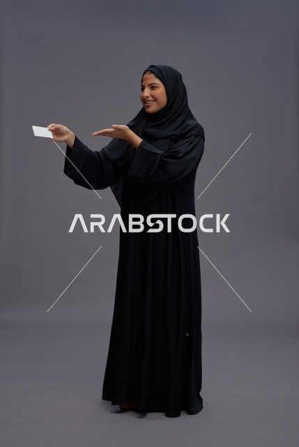 امرأة سعودية بالعباءة تحمل بطاقة فارغة