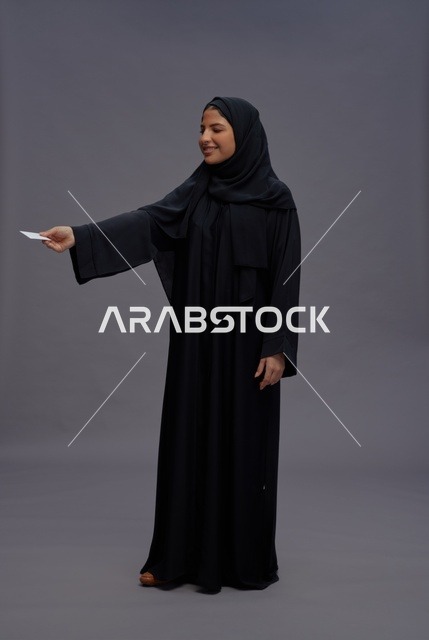 امرأة سعودية بعباية سوداء تحمل بطاقة فارغة