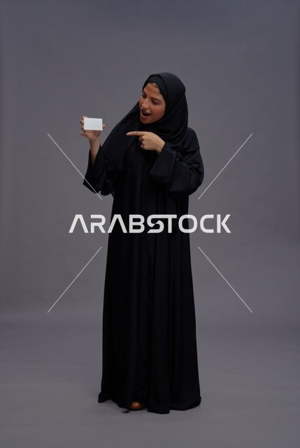 امرأة سعودية بعباية سوداء تشير لبطاقة فارغة