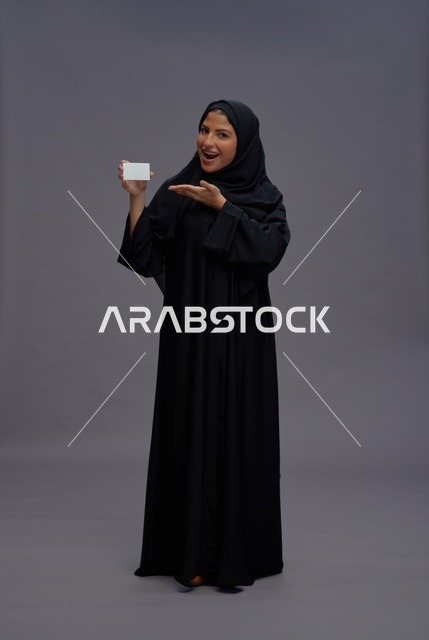 امرأة سعودية بعباءة سوداء تحمل بطاقة بيضاء فارغة