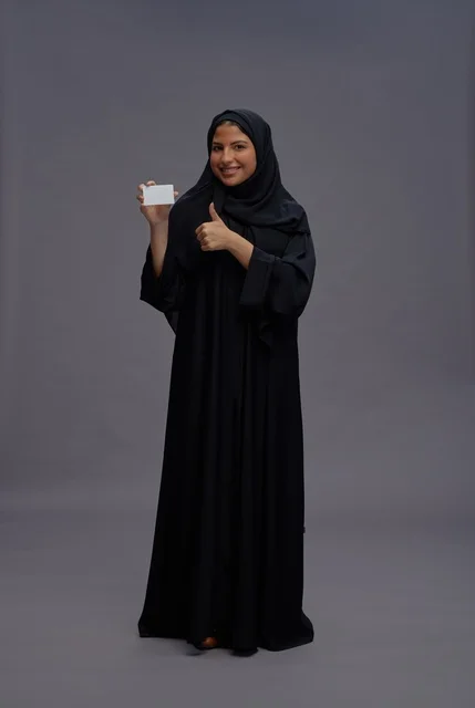 امرأة سعودية بالعباية تحمل بطاقة بيضاء فارغة