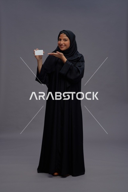 امرأة سعودية بعباية سوداء تحمل بطاقة عمل فارغة