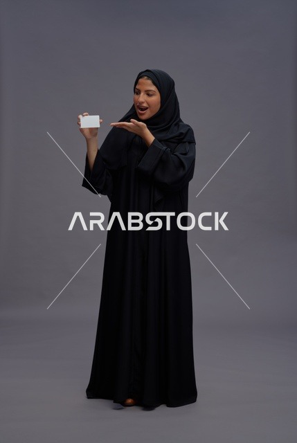 امرأة سعودية بعباءة سوداء تحمل بطاقة فارغة