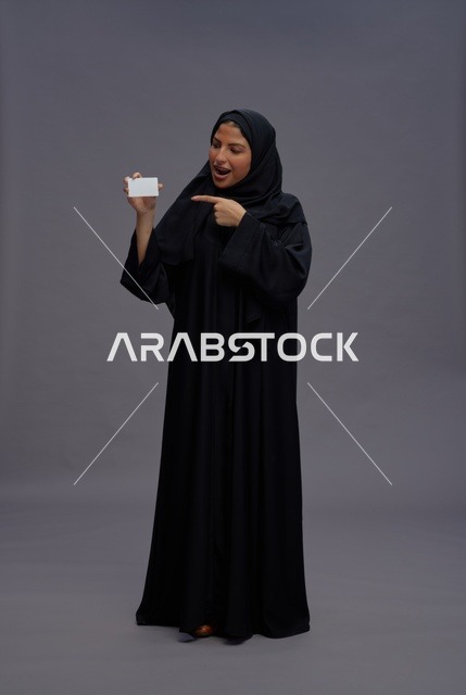 امرأة سعودية بعباية تشير إلى بطاقة عمل فارغة