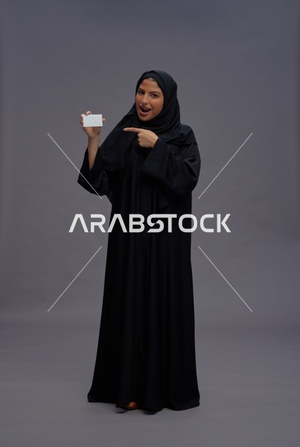 امرأة سعودية بالعباءة تحمل بطاقة فارغة في الاستوديو