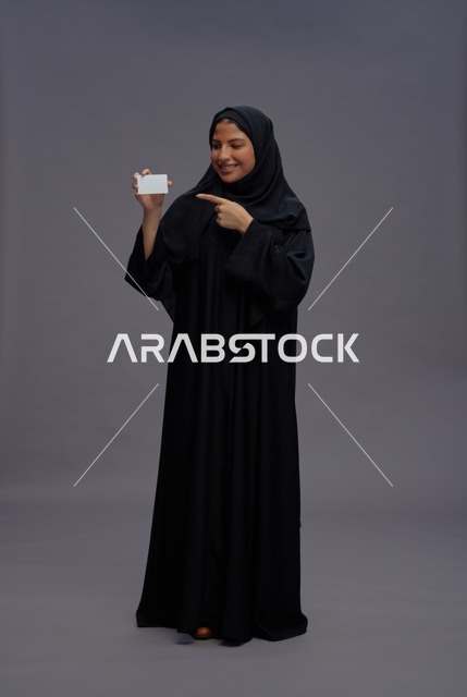 امرأة سعودية بعباية تحمل بطاقة بيضاء فارغة