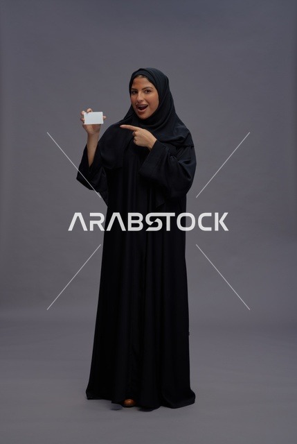 امرأة سعودية ترتدي عباءة سوداء تحمل بطاقة عمل فارغة