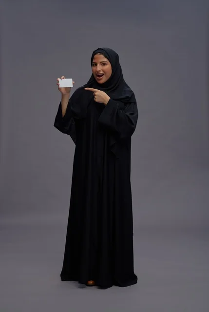 امرأة سعودية ترتدي عباءة سوداء تحمل بطاقة عمل فارغة