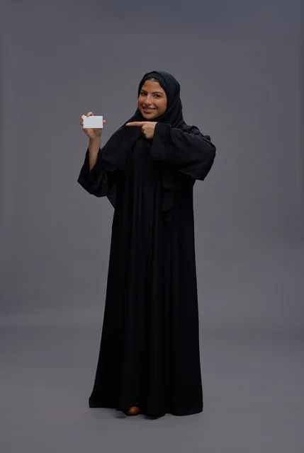 امرأة سعودية بعباية سوداء تحمل بطاقة بيضاء فارغة