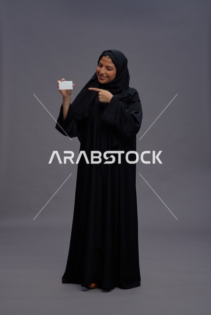 امرأة سعودية بالعباية تحمل بطاقة فارغة في الاستوديو