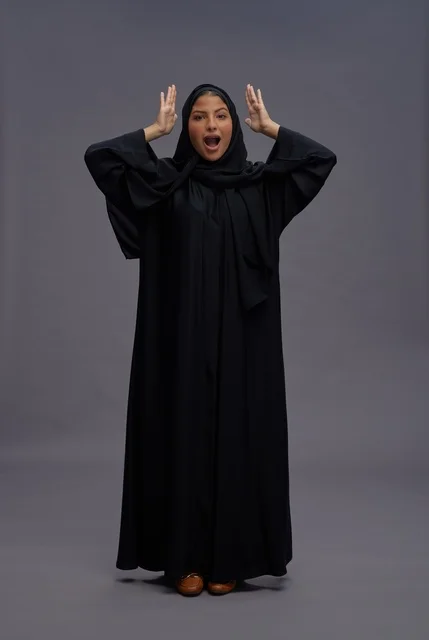 امرأة سعودية بعباية سوداء تعبر عن الدهشة والحماس