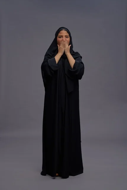 امرأة سعودية مبتهجة ترتدي عباية سوداء تعبر عن الحماس