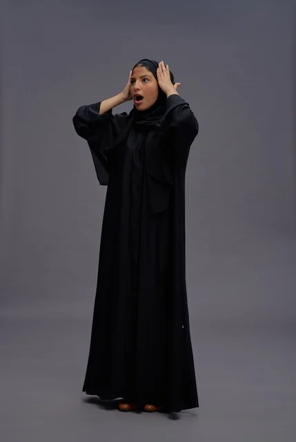 امرأة سعودية بعباءة سوداء تعبر عن المفاجأة والحماس