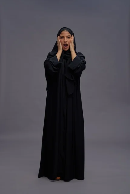 Surprised Saudi Woman in Black Abaya on Grey Background