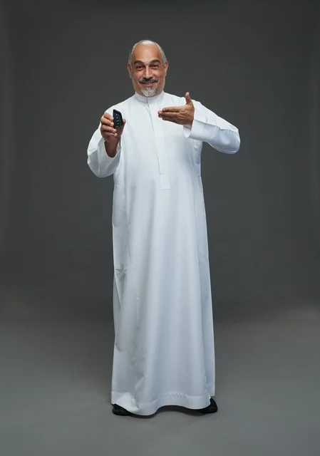 رجل سعودي مسن يحمل مفتاح سيارة في استوديو