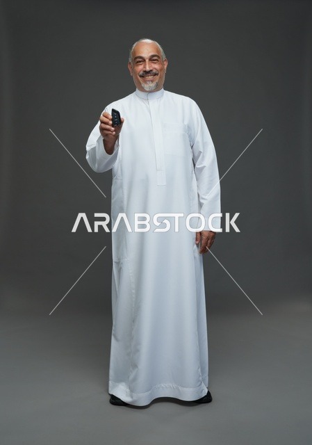 رجل سعودي مسن يرتدي ثوباً أبيض يحمل مفتاح سيارة