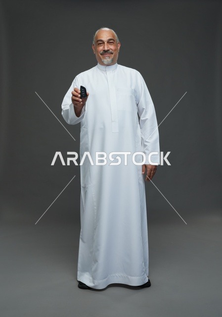 رجل سعودي مسن يحمل مفتاح سيارة في استوديو