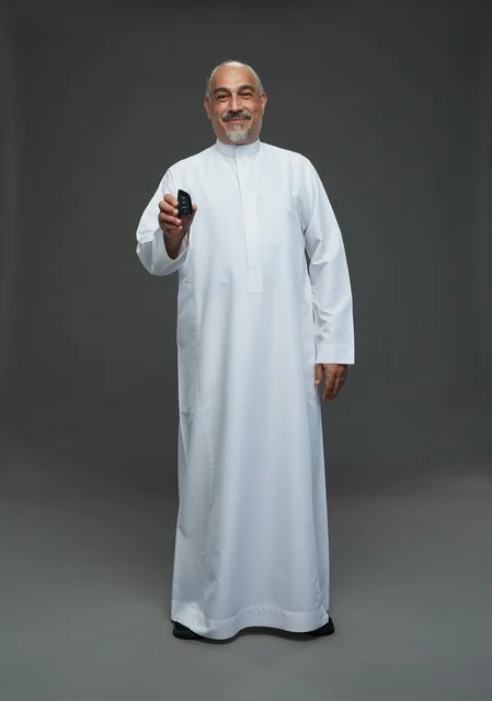 رجل سعودي مسن يحمل مفتاح سيارة في استوديو