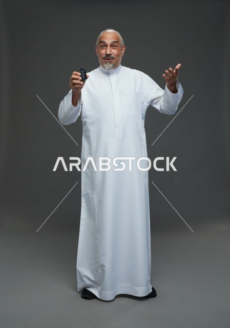 رجل سعودي مسن يحمل مفتاح سيارة في الاستوديو