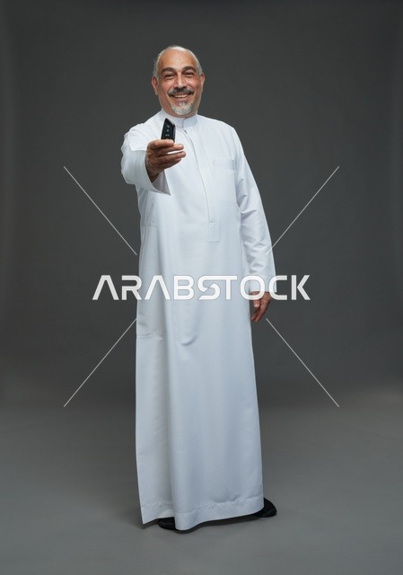 رجل سعودي مسن يحمل مفتاح سيارة في الاستوديو
