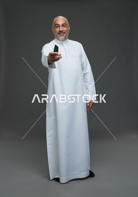 رجل سعودي مسن يحمل مفتاح سيارة في استوديو
